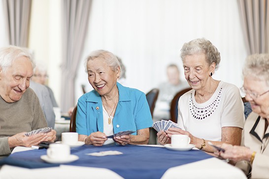 Group of seniors playing cards in a retirement home.