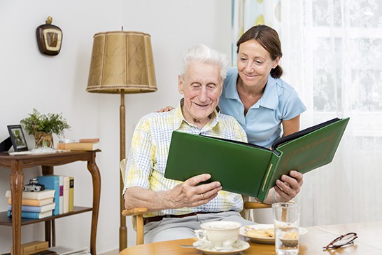 Caregiver with senior man and old photo album