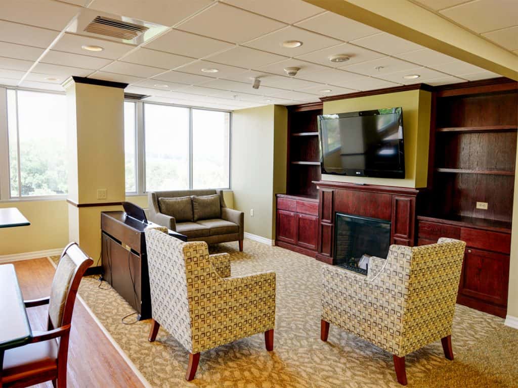 Community Room with fireplace, comfortable seating, and television at Edgerton Care Center in Edgerton, Wisconsin